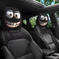 Car headrest covers with cartoonish faces in a vehicle interior.