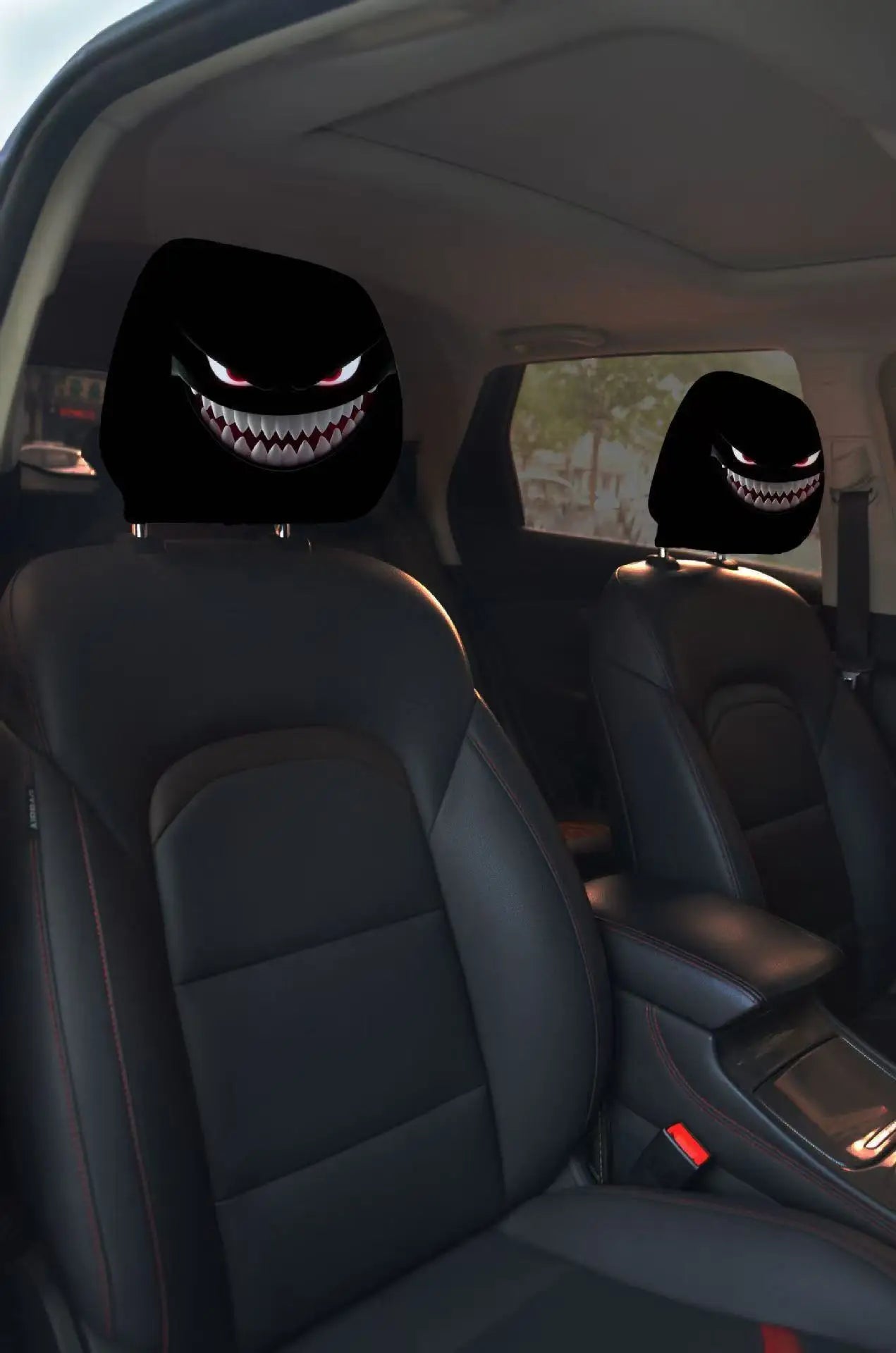Car interior with black headrest covers featuring menacing face designs.